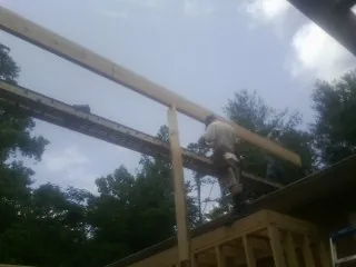 Carpenter setting a ridge beam over a new addition frame — Ice Dam Removal by Roofing Brothers in Hensonville