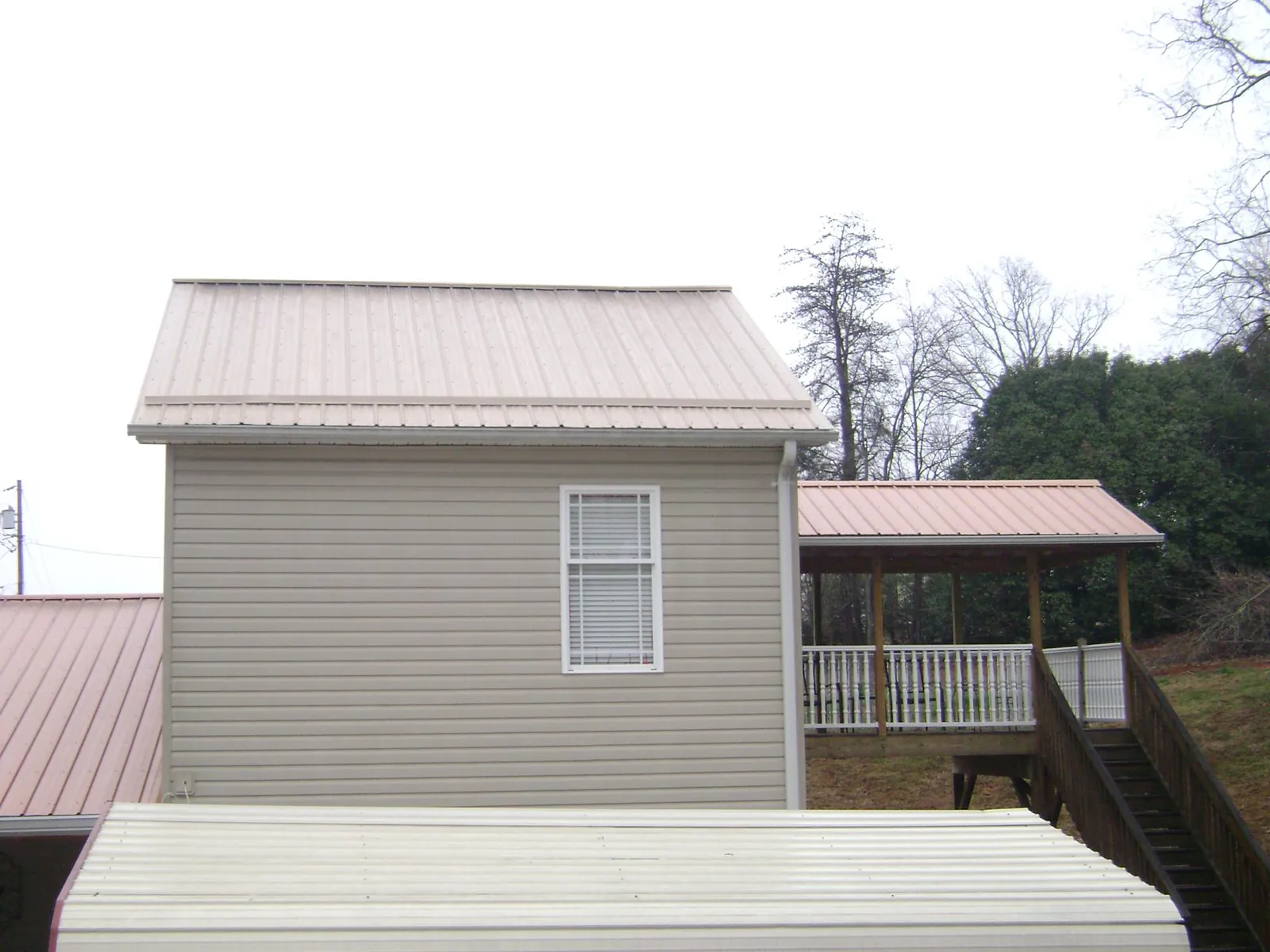 Tan metal roofs on a two story addition and attached porch, from a Roof Replacement job in Hensonville