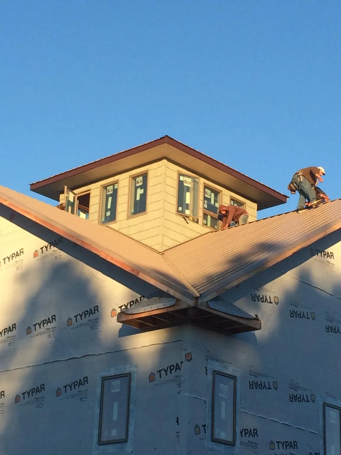 Roofers working around a rooftop cupola on a new metal roof at sunset — Roof Waterproofing in Hensonville by Roofing Brothers